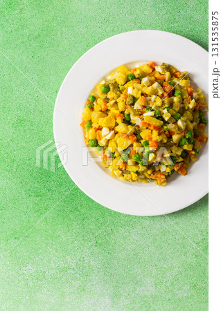 A vibrant salad showcases a mix of boiled egg, tender chicken breast, diced potatoes, sweet carrots, and green peas, all drizzled with olive oil, perfect as a nutritious meal A vibrant salad showcases a mix of boiled egg, tender chicken breast, diced potatoes, sweet carrots, and green peas, all drizzled with olive oil, perfect as a nutritious meal 131535875