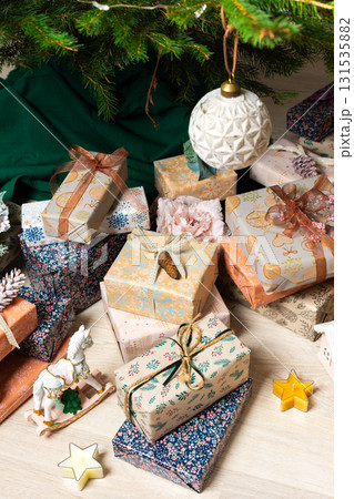 A cozy Christmas scene with elegant natural-toned gift boxes placed under a Christmas tree, lit with festive lights, evoking peace and seasonal joy A cozy Christmas scene with elegant natural-toned gift boxes placed under a Christmas tree, lit with festive lights, evoking peace and seasonal joy 131535882