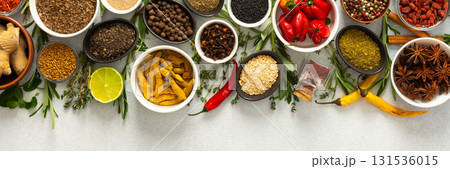 A vibrant assortment of spices and herbs on a gray background, offering a flavorful addition to any recipe, top view and copy space, banner 131536015
