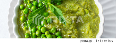 A bowl of vibrant green pea and broccoli soup is topped with fresh mint leaves for flavor. This healthy dish is perfect for a warm lunch or cozy dinner at home, banner A bowl of vibrant green pea and broccoli soup is topped with fresh mint leaves for flavor. This healthy dish is perfect for a warm lunch or cozy dinner at home, banner 131536105