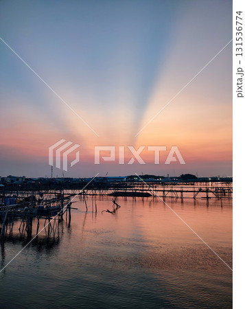 Beautiful sunset over a coastal village with dramatic sun rays, calm waters, and traditional fishing structures. Perfect for travel, nature, and scenic themes. Beautiful sunset over a coastal village with dramatic sun rays, calm waters, and traditional fishing structures. Perfect for travel, nature, and scenic themes. 131536774