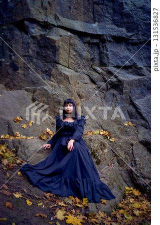 a woman in a black long dress sitting on black rocks on Halloween, modern witch 131536827