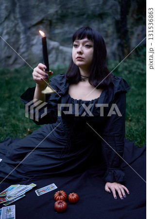 two women in black long dresses sitting on the black rocks on Halloween, reading tarot cards, performing a witch ritual, modern witch 131536863
