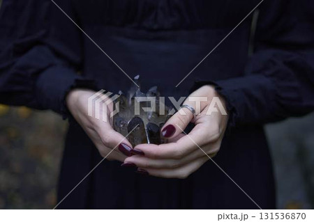 a woman in a black long dress near black rocks on Halloween holding a purple black crystal, performing a witch ritual, modern witch a woman in a black long dress near black rocks on Halloween holding a purple black crystal, performing a witch ritual, modern witch 131536870