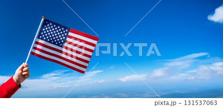 青空を背景に子供の手が小さなアメリカの国旗を持っている。 青空を背景に子供の手が小さなアメリカの国旗を持っている。 131537063
