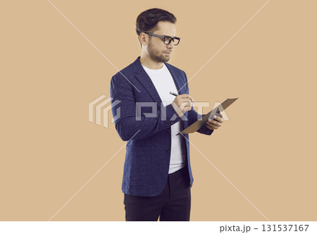 Business man or sales manager in suit and glasses writing something on clipboard 131537167
