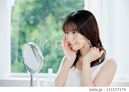 鏡で肌の状態を確認する笑顔の女性 131537174