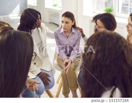 Diverse women supporting a sad young girl during a group therapy meeting session Diverse women supporting a sad young girl during a group therapy meeting session 131537184
