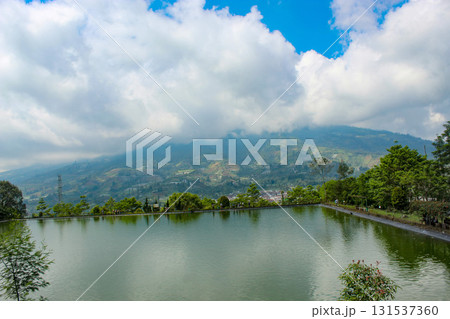 Panoramic landscape showcasing a tranquil pond and distant misty hills, highlighted by a vibrant sky. Panoramic landscape showcasing a tranquil pond and distant misty hills, highlighted by a vibrant sky. 131537360