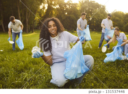Volunteers friends collecting plastic litter in bags, cleaning park from pollution Volunteers friends collecting plastic litter in bags, cleaning park from pollution 131537446