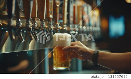 Close-up of male hand pouring beer into glass at bar counter. 131537633