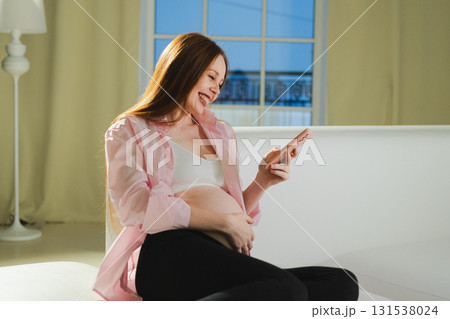 Pregnancy motherhood. Pregnant woman with smartphone typing scrolling at home. Woman with cell phone enjoying pregnancy surfing internet using social media apps. Mobile application for pregnant women 131538024