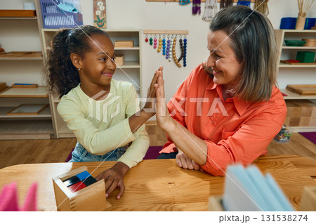 Teacher and child celebrating success with high five after learning task Teacher and child celebrating success with high five after learning task 131538274