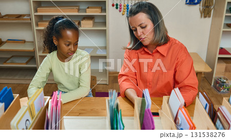 Teacher supporting girl during classroom activity with learning materials Teacher supporting girl during classroom activity with learning materials 131538276