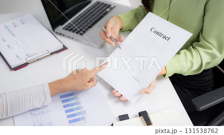 Adult Asian business professionals review contract terms collaborate office environment negotiation strategy discuss important business agreement deal 131538762