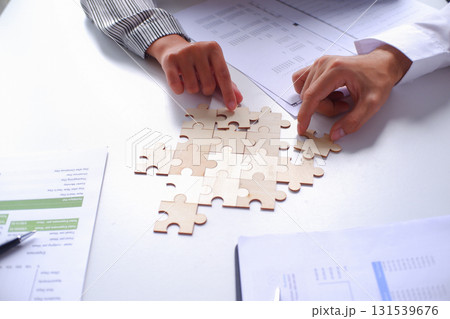 Closeup hands of two business people helping each other connecting jigsaw puzzle. Business solutions, success and strategy concept. 131539676