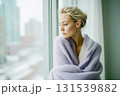 A woman in a purple sweater is looking out the window 131539882