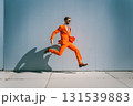 A man in an orange suit is running and jumping in front of a wall 131539883