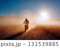 A man is riding a motorcycle in a dusty, foggy desert 131539885