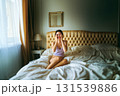 A woman is sitting on a bed with her hands on her face 131539886