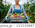 A woman is holding a crate of vegetables in a greenhouse 131539887
