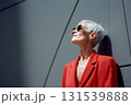 A woman in a red jacket is standing in front of a wall 131539888