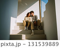 A couple sitting on a staircase with a laptop in front of them 131539889