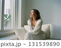 A woman is sitting on a couch with her head tilted to the side 131539890