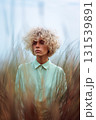 A woman with blonde hair stands in a field of tall grass 131539891