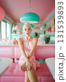 A woman in a pink dress sits in a pink booth at a diner 131539893