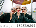 Three women in sunglasses and leather jackets are posing for a selfie 131539895
