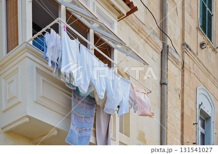 Malta balcony with hanging laundry on limestone facade in Valletta old town 131541027