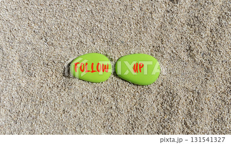 Follow up symbol. Concept word Follow up on beautiful green stones. Sea sand beach. Beautiful sand beach background. Business follow up concept. Copy space. 131541327