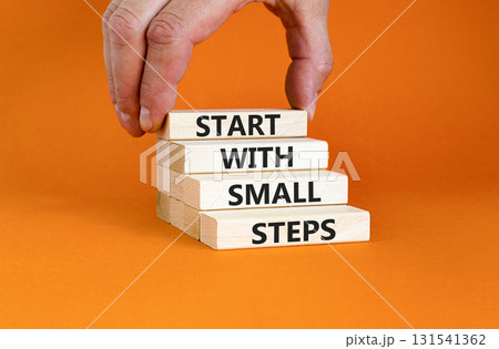 Start with small steps symbol. Concept words phrase Start with small steps on beautiful wooden blocks. Beautiful orange background. Businessman hand Business Start with small steps concept. Copy space Start with small steps symbol. Concept words phrase Start with small steps on beautiful wooden blocks. Beautiful orange background. Businessman hand Business Start with small steps concept. Copy space 131541362
