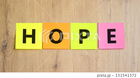 Hope symbol. Concept word Hope on beautiful colored paper. Beautiful wooden table wooden background. Business, lifestyle, support and hope concept. Copy space. Hope symbol. Concept word Hope on beautiful colored paper. Beautiful wooden table wooden background. Business, lifestyle, support and hope concept. Copy space. 131541372