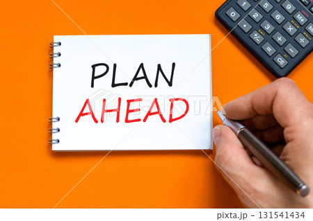 Plan ahead symbol. Concept word Plan ahead on beautiful white note. Businessman's hand. Black calculator. Beautiful orange paper background. Business plan ahead concept. Copy space. 131541434