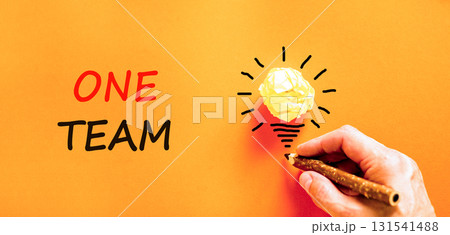 One team symbol. Concept word One team on beautiful orange paper. Businessman's hand. Light bulb icon. Beautiful orange paper background. Business one team concept. Copy space. 131541488