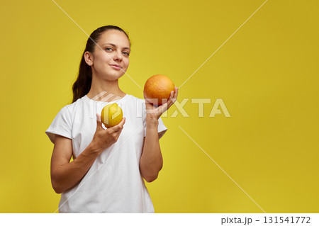 happy woman holding fresh lemon and grapefruit on yellow studio background happy woman holding fresh lemon and grapefruit on yellow studio background 131541772