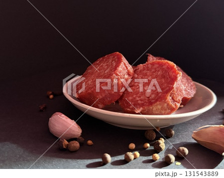 Slices of salami with garlic and pepper. Salami slices with shallots and peppercorns. Slices of salami with garlic and pepper. Salami slices with shallots and peppercorns. 131543889