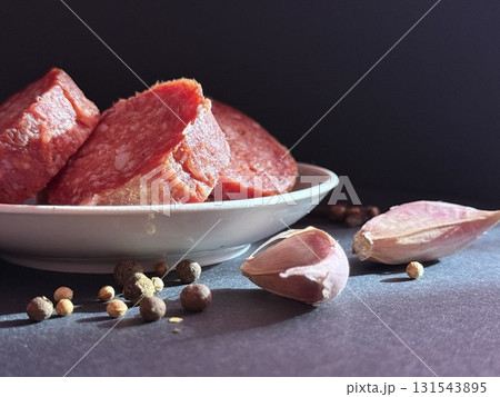Slices of salami with garlic and pepper. Salami slices with shallots and peppercorns. 131543895