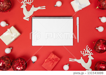Christmas composition of gift boxes and toys on Christmas tree, with an open blank notebook and pen on red background for writing goals and plans for the New Year. Flat lay, copy space Christmas composition of gift boxes and toys on Christmas tree, with an open blank notebook and pen on red background for writing goals and plans for the New Year. Flat lay, copy space 131543899