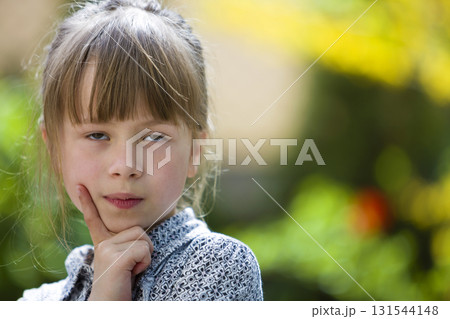 Portrait of cute pretty thoughtful child girl outdoors on blurred sunny colorful bright background. 131544148