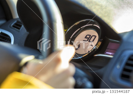 Modern car interior with driver hand on steering wheel and ninety km on speedometer. Safe driving concept. Modern car interior with driver hand on steering wheel and ninety km on speedometer. Safe driving concept. 131544187