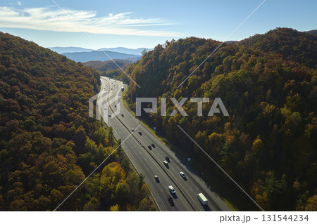 I-40 freeway road leading to Asheville in North Carolina thru Appalachian mountains with yellow fall forest and fast moving trucks and cars. Concept of high speed interstate transportation 131544234