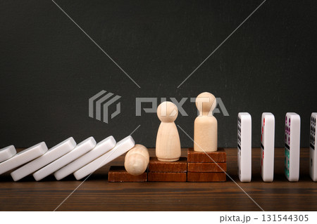 Domino Effect with Wooden Figures on a Dark Background Domino Effect with Wooden Figures on a Dark Background 131544305