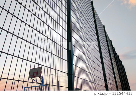 High wire mesh fence in restricted area on blue sky background. High wire mesh fence in restricted area on blue sky background. 131544413