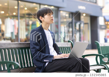 ベンチに座ってパソコン作業をする20代男性 ベンチに座ってパソコン作業をする20代男性 131545065