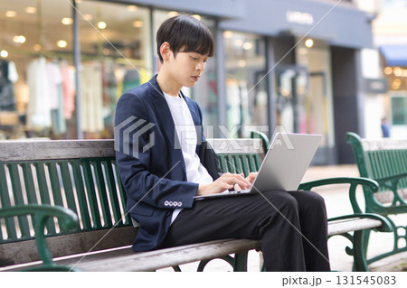 ベンチに座ってパソコン作業をする20代男性 ベンチに座ってパソコン作業をする20代男性 131545083
