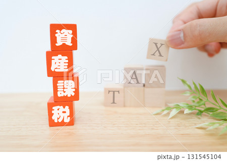 資産課税を示す赤ブロック。背後の階段上に積み上げた積み木にTAXの文字。 131545104