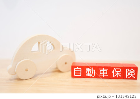 木製の車と自動車保険の文字ブロック。コピースペースあり。 木製の車と自動車保険の文字ブロック。コピースペースあり。 131545125